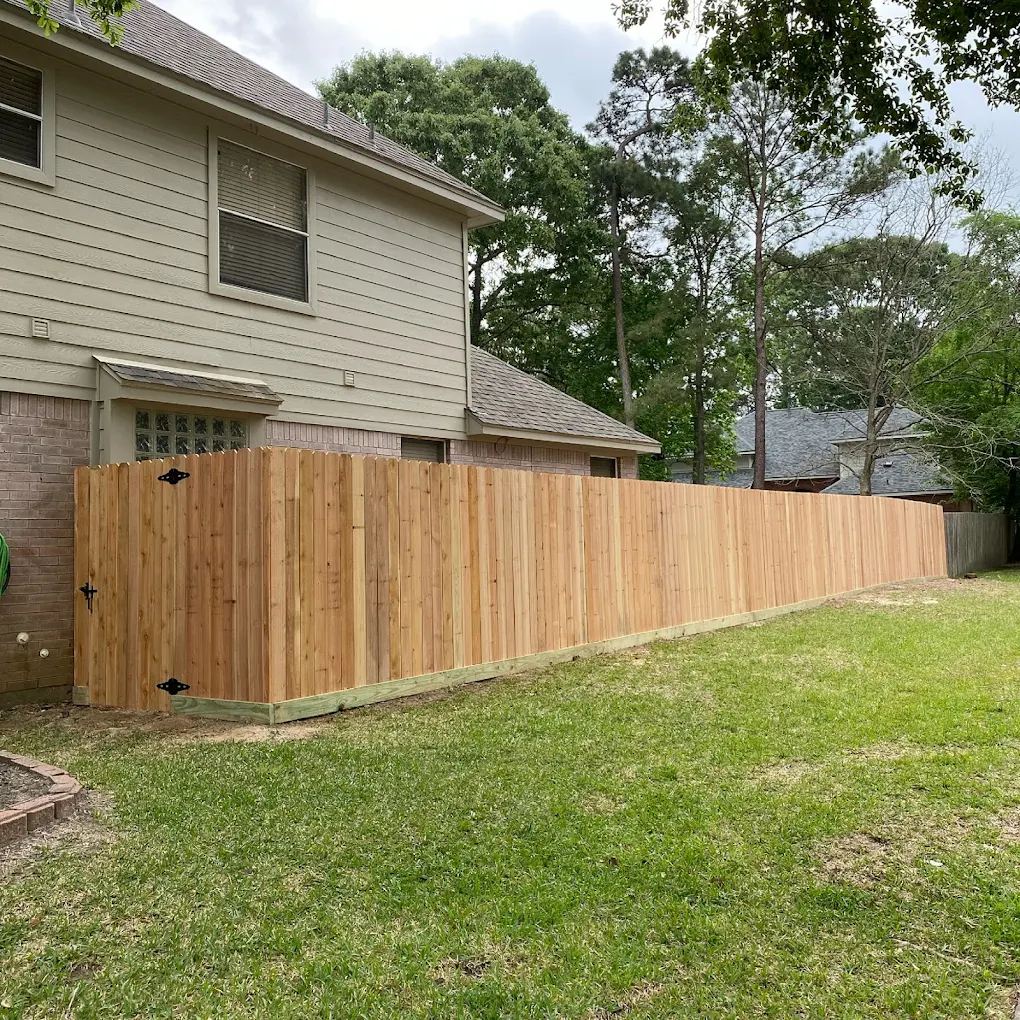 New cedar privacy fence with a matching gate running along the side of a two-story home