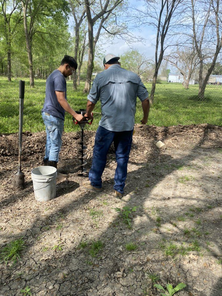 Two Penaloza Broz crew members boring post holes with a power auger on a rural property